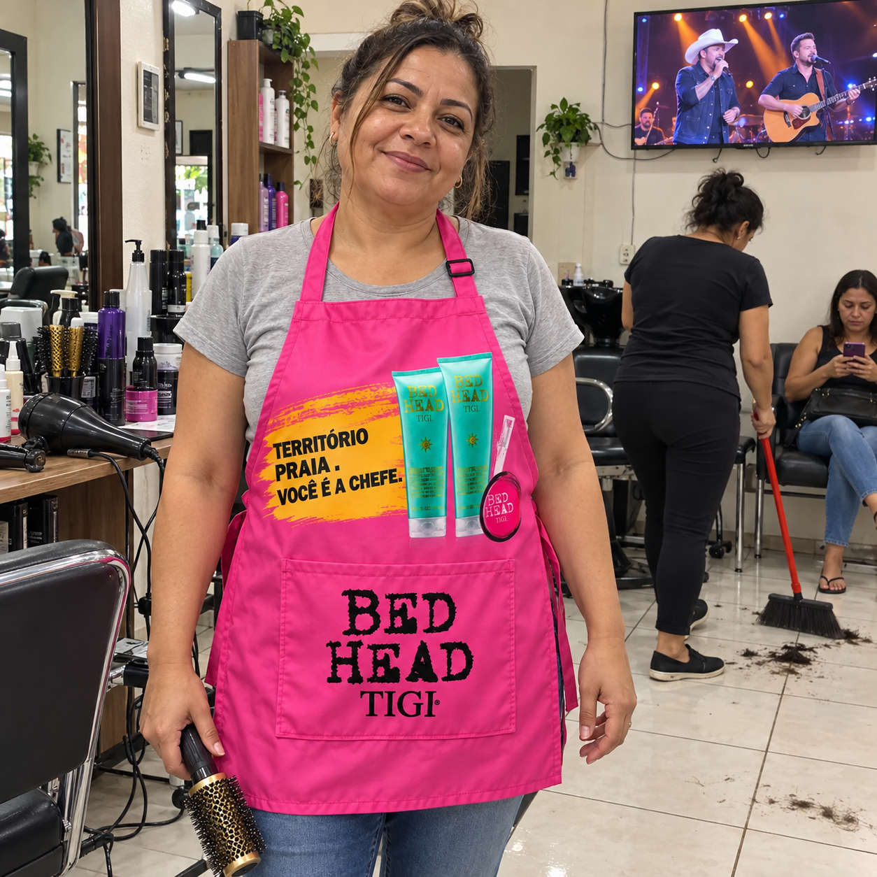 Avental personalizado para brindes: cabeleireira usando avental rosa da Bed Head TIGI com a campanha Território Praia, você é a chefe, em salão de beleza