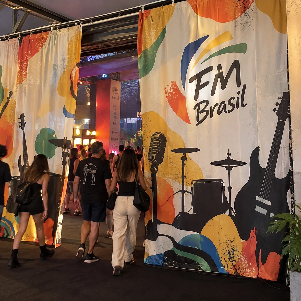 Cortinas personalizadas para evento impressas em tecido com a logo da FM Brasil e ilustrações de instrumentos musicais na entrada do festival